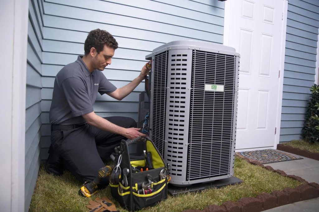 A man diligently works on an air conditioning unit, adjusting components to restore its functionality.