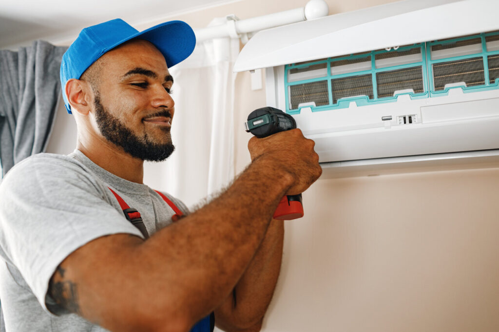 A professional is fixing an air conditioner, demonstrating expertise in HVAC maintenance and repair.