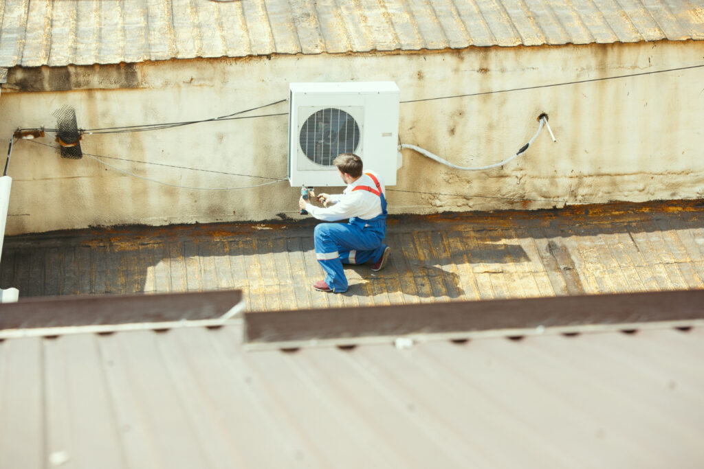 A man is engaged in repairing an air conditioning system, ensuring it operates efficiently for indoor comfort.